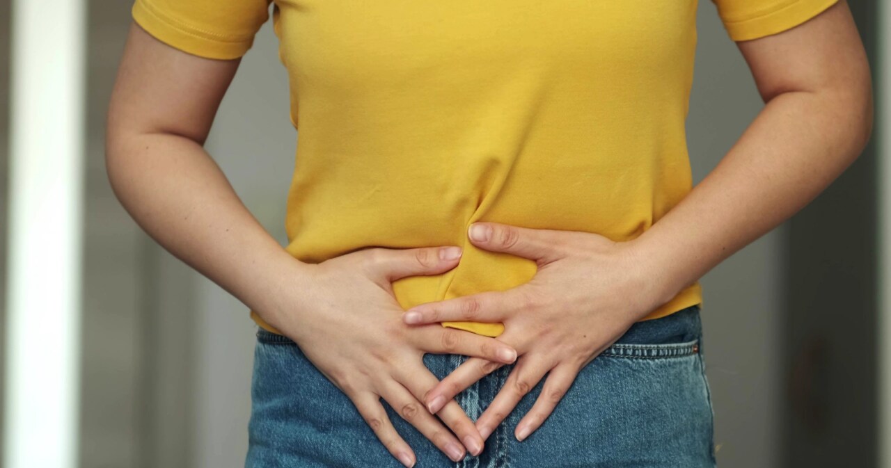 Frau hält sich den Bauch aufgrund von Magen- oder Gallenschmerzen.